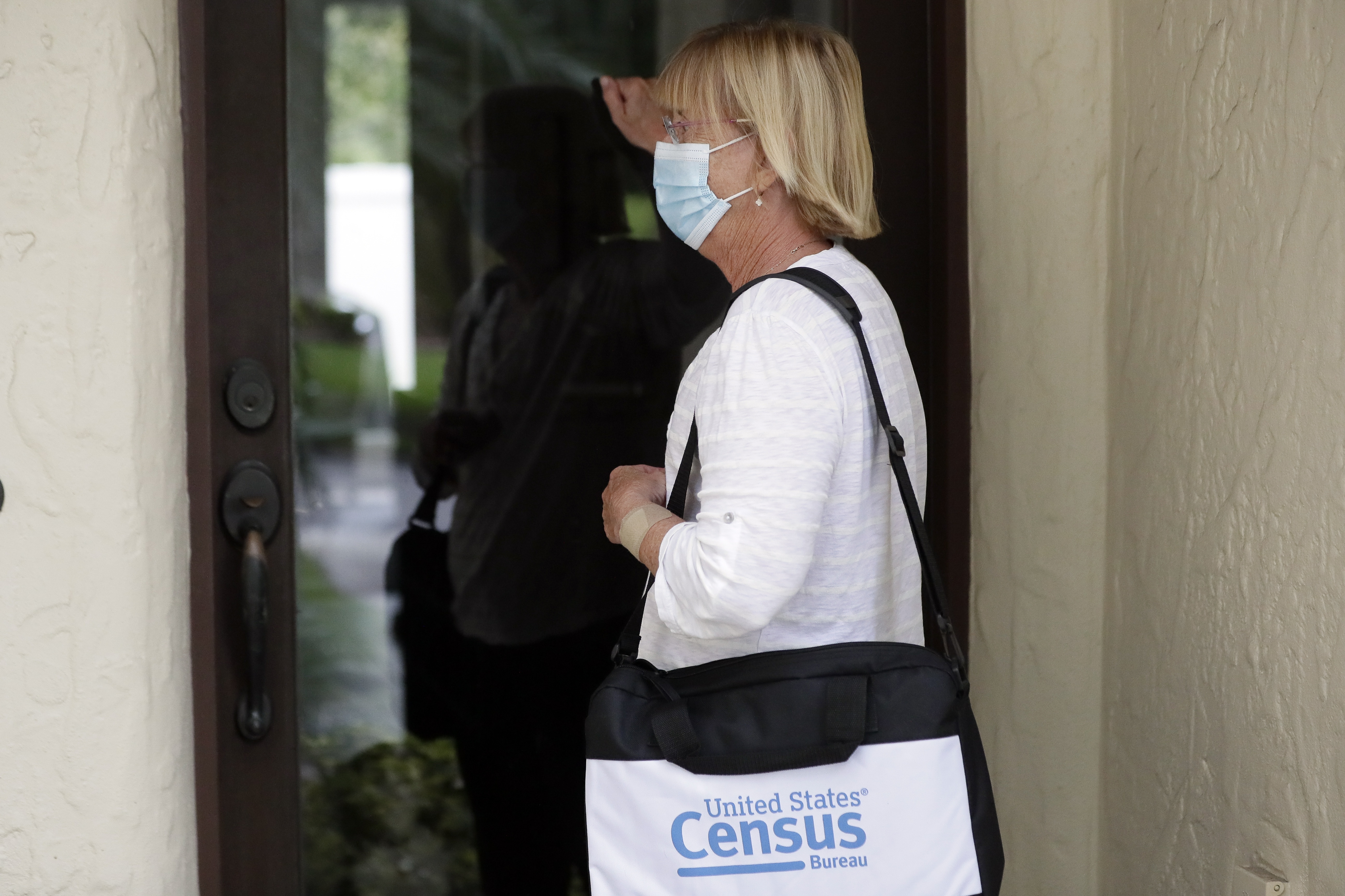 A Census Bureau worker knocks on the door of a home in Winter Park, Fla., in 2020.